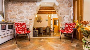 A cozy room with stone walls, a wooden ceiling, and a dining area with two red chairs and a table. - House Kras (Kras)