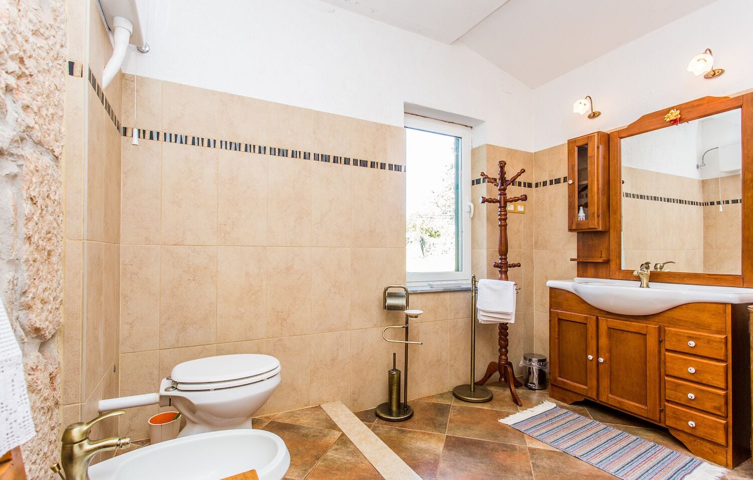 Un baño con inodoro, lavabo y tocador de madera.
