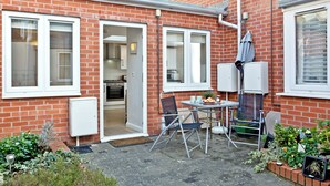 A brick house with a small patio, a dining table, and a chair.