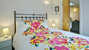 A bed with a floral bedspread, a bedside lamp, and a wall-mounted light fixture.