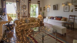 A cozy living room with a glass coffee table, a sofa, and a dining area with a table. - Villa Wisteria (Funchal)