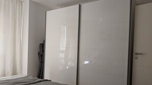 Ein Schlafzimmer mit Bett, Kleiderschrank und einem fenster mit Vorhängen.