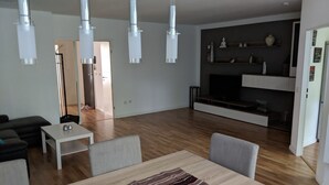 Ein modernes Wohnzimmer mit Essbereich, Holzböden und einem an der Wand befestigten Flachbildfernseher.