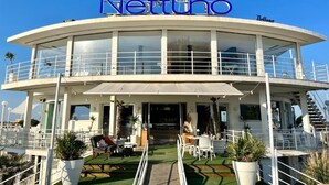 Un bâtiment moderne à deux étages, doté d’un toit incurvé et d’un balcon. Le nom « Nettono » est affiché en grand sur la façade.