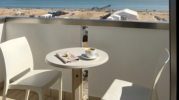 Un balcon avec une table, des chaises et une vue sur la plage.
