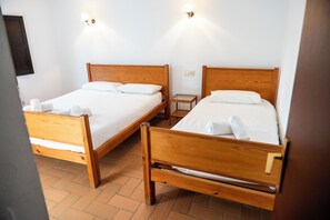 Two wooden beds with white linens and towels, a small bedside table, and a wall-mounted light fixture. - MASOVERS A, 3 bedrooms, 1–6 people (max. 8—2 on a sofa bed), 5 min. from the beach (Castelló d'Empúries)