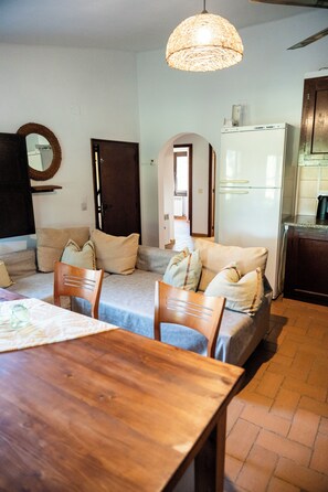 A cozy living room with a sofa, a wooden dining table, and a hanging light fixture. - MASOVERS A, 3 bedrooms, 1–6 people (max. 8—2 on a sofa bed), 5 min. from the beach (Castelló d'Empúries)