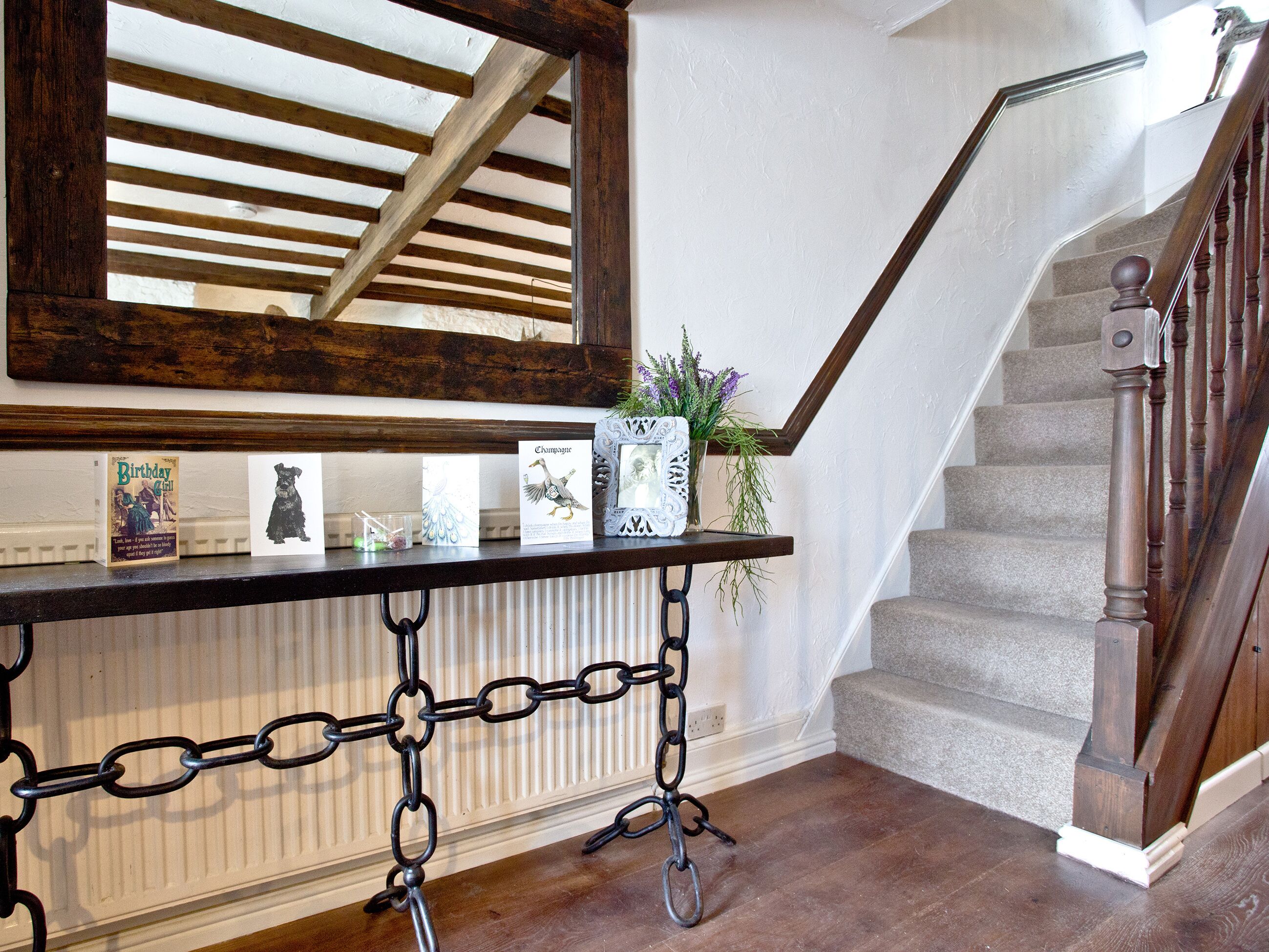 Eine Treppe mit hölzernen Geländern, ein Tisch aus schwarzem Metall mit Karten und eine weiße Heizung.