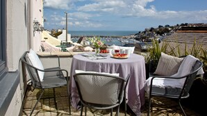 En terrasse med et bord til to, med udsigt over en havn og en kystby.