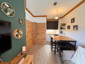 A compact living space with a dining area, kitchenette, and a television.