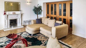 Ein Wohnzimmer mit Ecksofa, Kamin, großem Holzschrank und dekorativem Teppich.