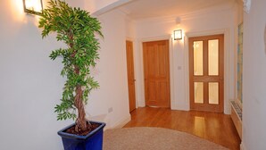 Ein Flur mit einem Bonsai-Baum im Topf, Holztüren und Wandleuchten.