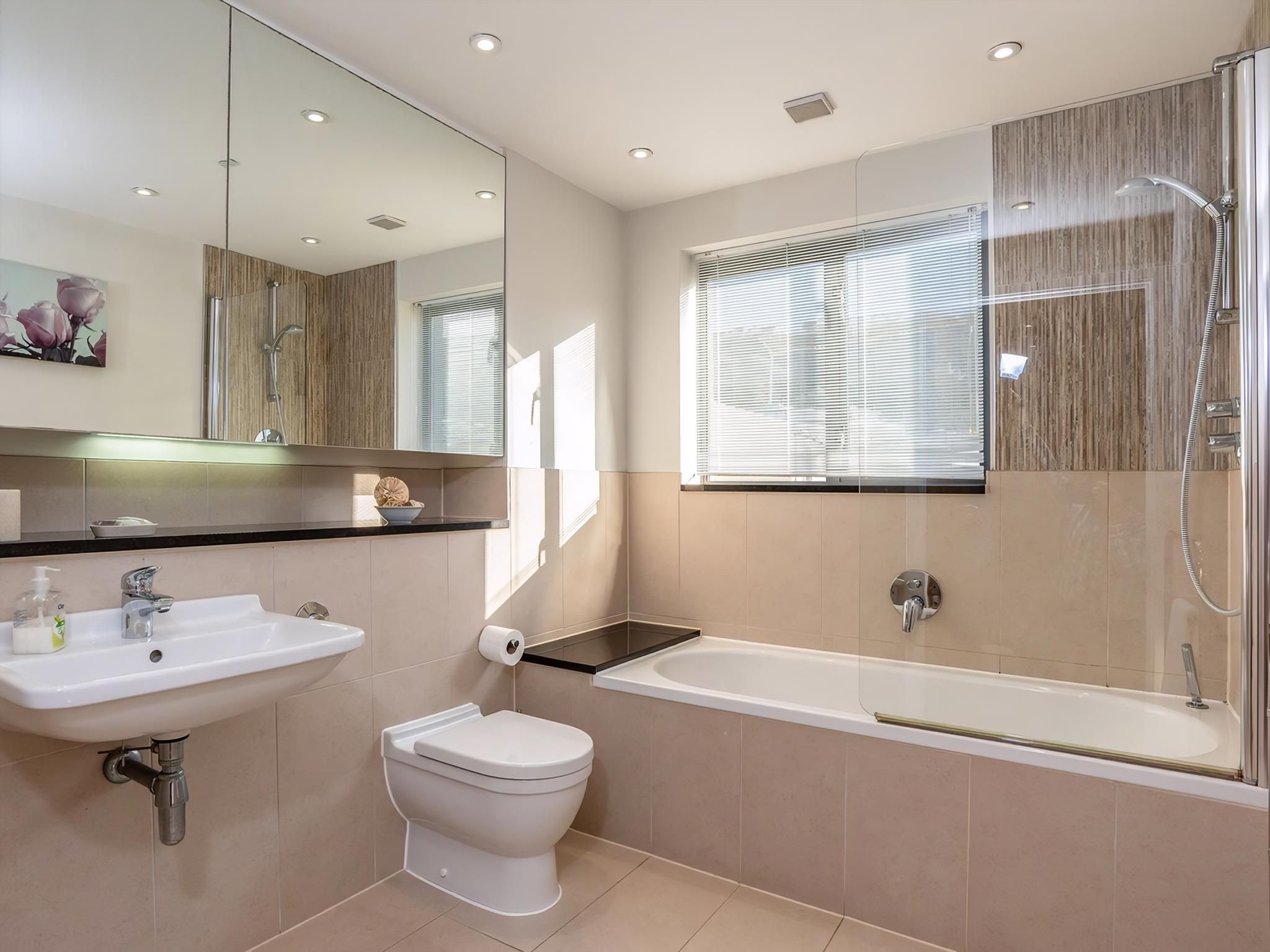 A modern bathroom with a sink, toilet, and bathtub.