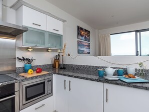 Una cocina moderna con electrodomésticos de acero inoxidable, armarios blancos y encimera de granito.