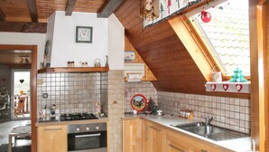 A kitchen with wooden cabinets, a gas stove, a sink, and a window with a view. - Homerez - House in Triembach-au-Val (Triembach-au-Val)