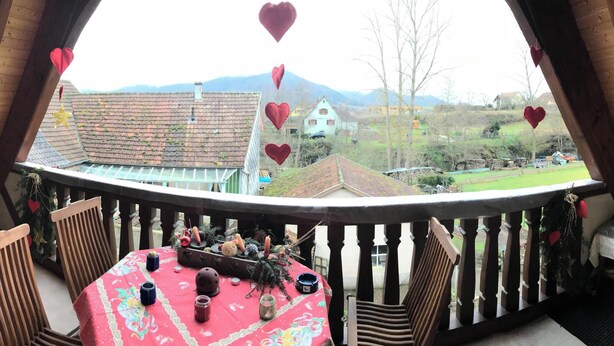 A wooden balcony with a table and chairs, decorated with heart-shaped ornaments and a star. - Homerez - House in Triembach-au-Val (Triembach-au-Val)