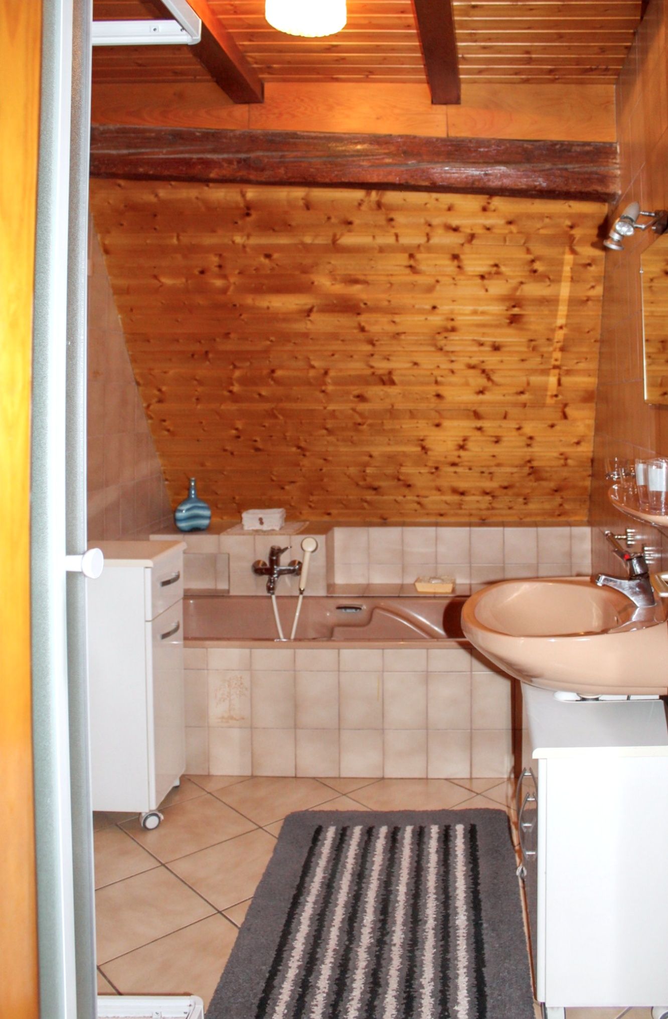 Ein Badezimmer mit Holzboden, einer Badewanne, einem Waschbecken und einem kleinen Schrank.