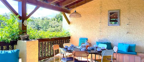 An outdoor patio with a table set for dining, surrounded by chairs and a sofa.
