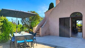 Un patio exterior con una mesa y sillas, una sombrilla y una escalera que lleva a una entrada.