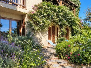 Un jardin avec un sentier menant à une porte en bois, entouré de différentes plantes et fleurs.