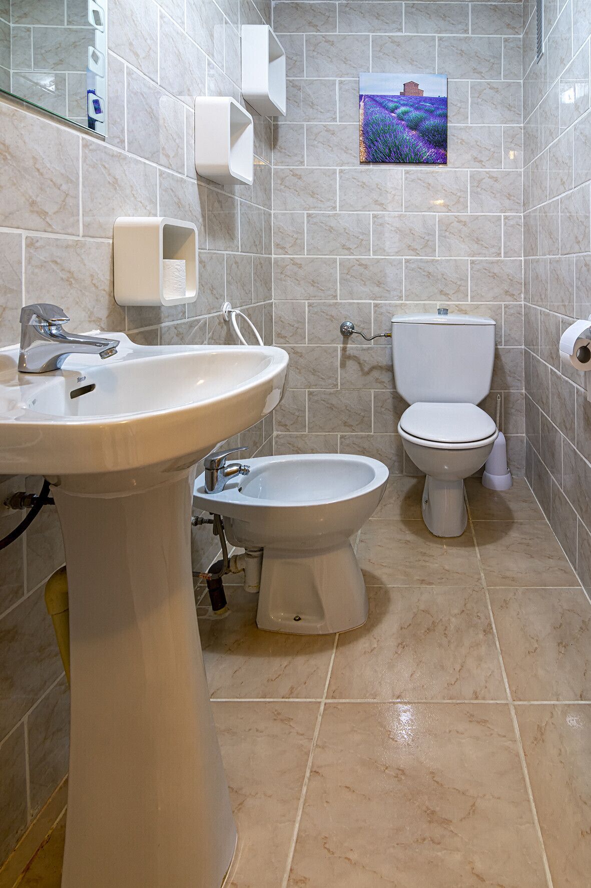 Une salle de bain équipée d’un lavabo, d’un bidet, de toilettes et de carreaux de marbre.