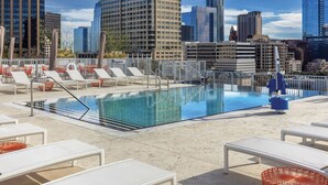 A rooftop pool with lounge chairs and tables, surrounded by high-rise buildings. - Downtown Austin 2 Bedroom Deluxe with Rooftop Pool in the Heart of everything (Austin)