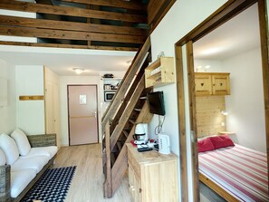 Experience a cozy retreat with a comfortable seating area, kitchenette, and a bed with a striped bedspread.