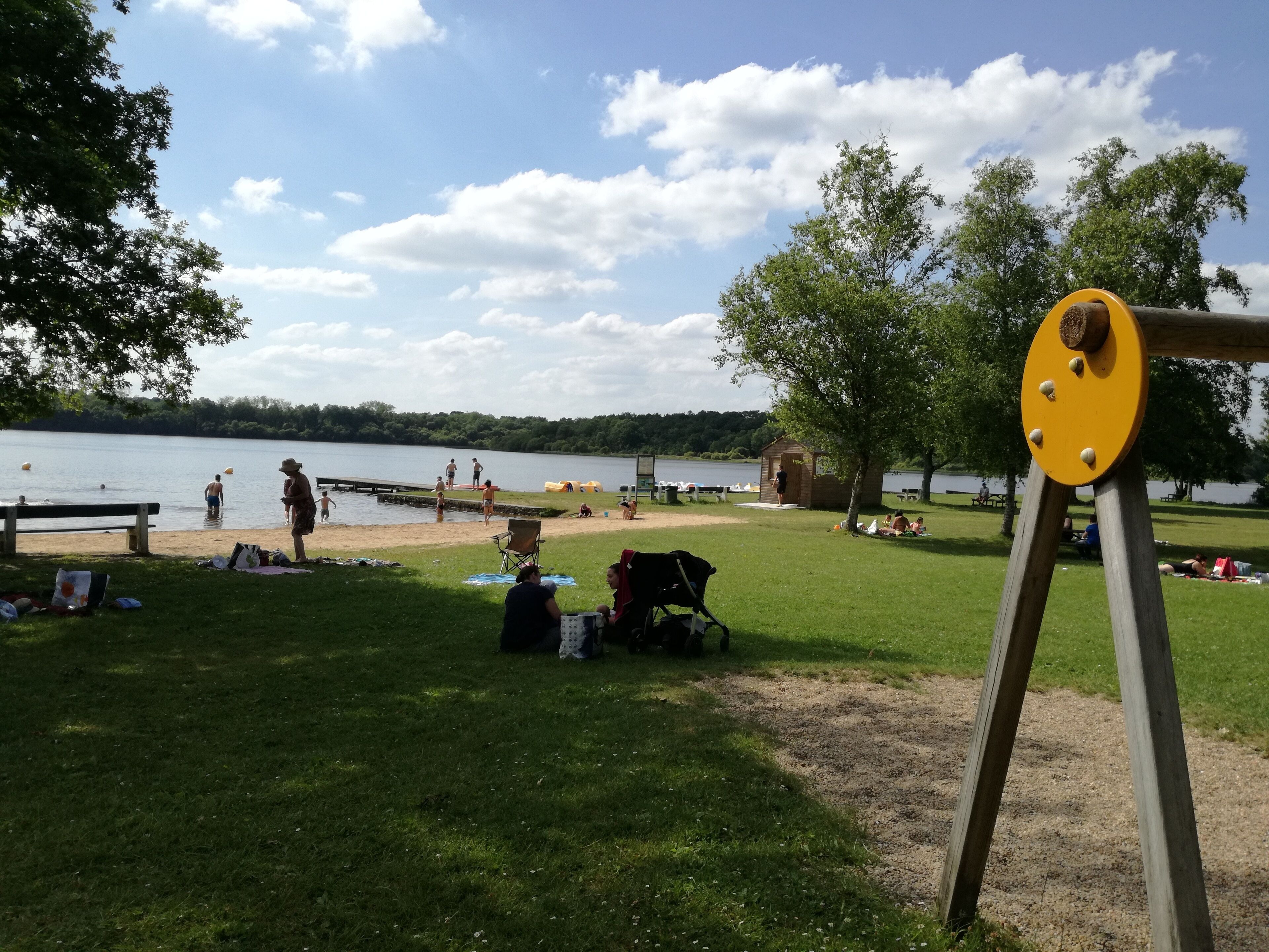 Un parc au bord du lac, doté d’une aire de jeux, d’espaces aménagés pour pique-niquer et d’une petite structure en bois.