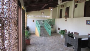 A covered outdoor area with a stone floor, a green metal staircase, and potted plants. - Pousada Ecobaía (Baia Formosa)