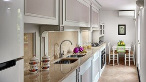 A modern kitchen with white cabinets, a stainless steel sink, and a dining area with a table and chairs. - Sophia - Lovely Apartment   (Meta)