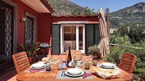 An outdoor dining area with a table set for two, a bottle, and various dishes. - Sophia - Lovely Apartment   (Meta)