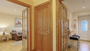 Una habitación con puertas de madera, un sofá, una mesita y un taburete.