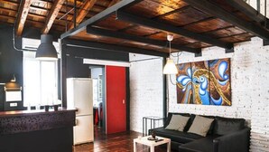 Un salon moderne avec un canapé noir, une table basse et une porte rouge donnant sur une autre pièce.