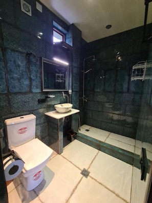 A bathroom with a toilet, sink, and glass-enclosed shower area.