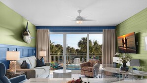 Quarto com vista para a piscina, ventoinha no teto e área de refeições com uma cesta de frutas.