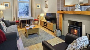 Un salon chaleureux avec une cheminée, un téléviseur et un coin salon confortable.