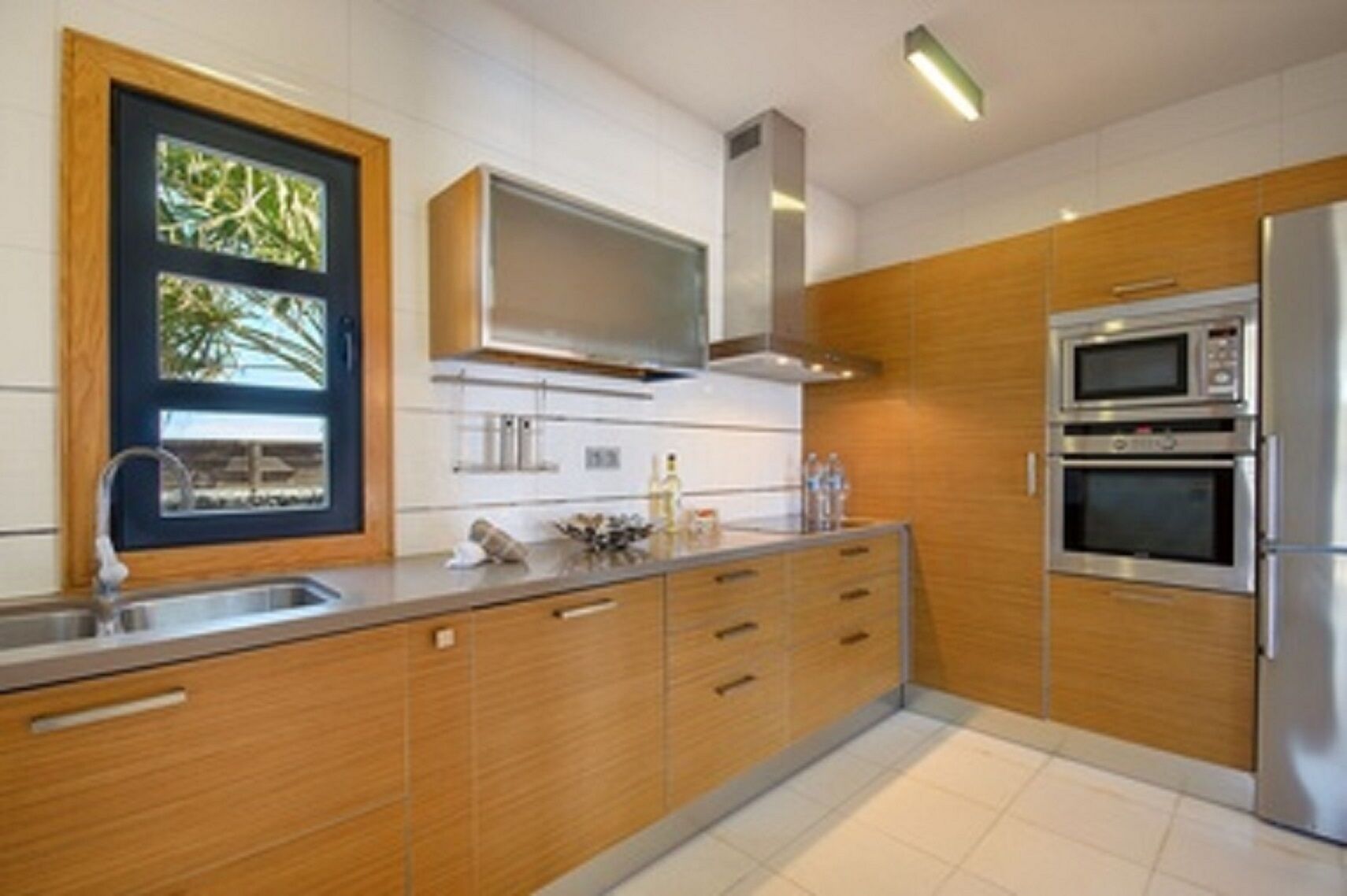 A modern kitchen with wooden cabinets, stainless steel appliances, and a built-in microwave.