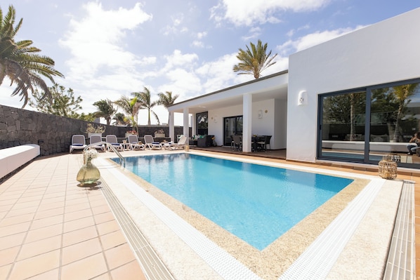 A swimming pool with lounge chairs and a stone wall.
