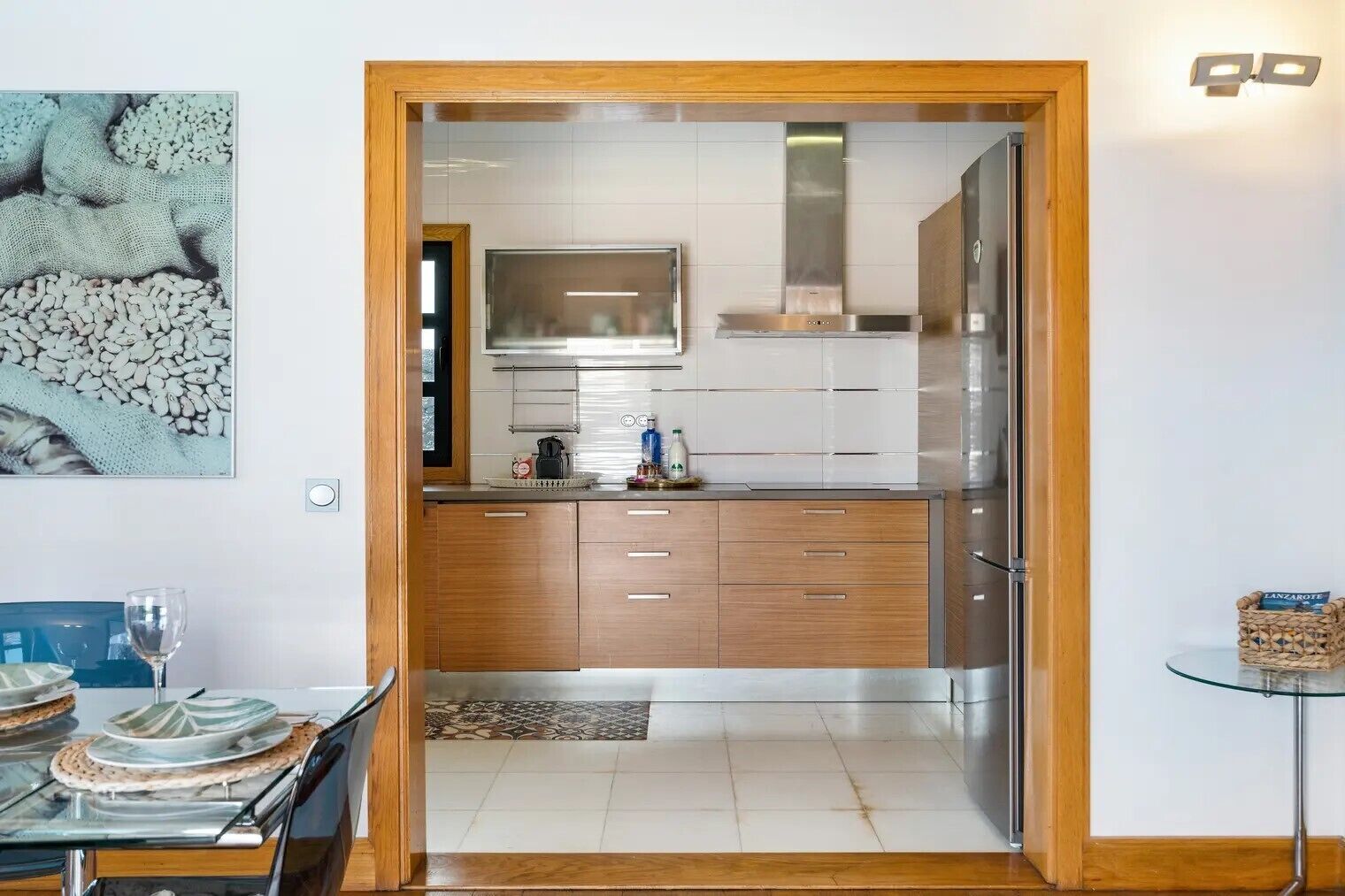 A modern kitchen with stainless steel appliances, wooden cabinets, and a glass door leading to the dining area.