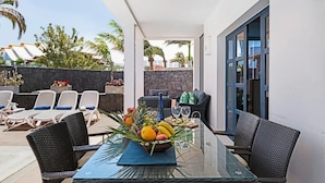 A sunlit outdoor patio with a glass table, wicker chairs, and a fruit centerpiece. - Luxury villas Mamma Mía Villa A Parking & pool private (Playa Blanca)