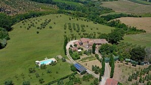 An aerial view of a rural property with a large field, a swimming pool, and a solar panel array.