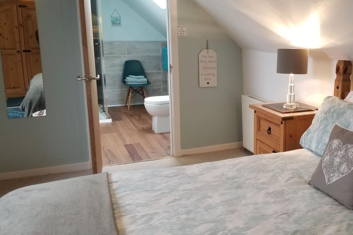 A bedroom with a bed, bedside table, lamp, and a wall with a decorative sign.