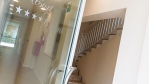 A hotel interior with a glass door featuring the name 'Resort Cupra' and a staircase with a metal railing. - Resort Cupra (Cupra Marittima)