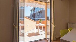 A balcony with a table and chairs, a potted plant, and a view of a building with balconies. - Resort Cupra (Cupra Marittima)
