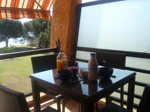 A table with breakfast items on a balcony overlooking a body of water. - CORSE STUDIO FEET IN WATER BY THE SEA (CORSE MORIANI)