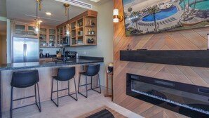 A modern kitchen with a bar area, wooden cabinetry, and a large island with bar stools.
