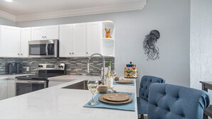 Una cocina moderna con armarios blancos, electrodomésticos de acero inoxidable y un salpicadero de azulejos.