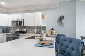 A modern kitchen with white cabinets, stainless steel appliances, and a tiled backsplash.