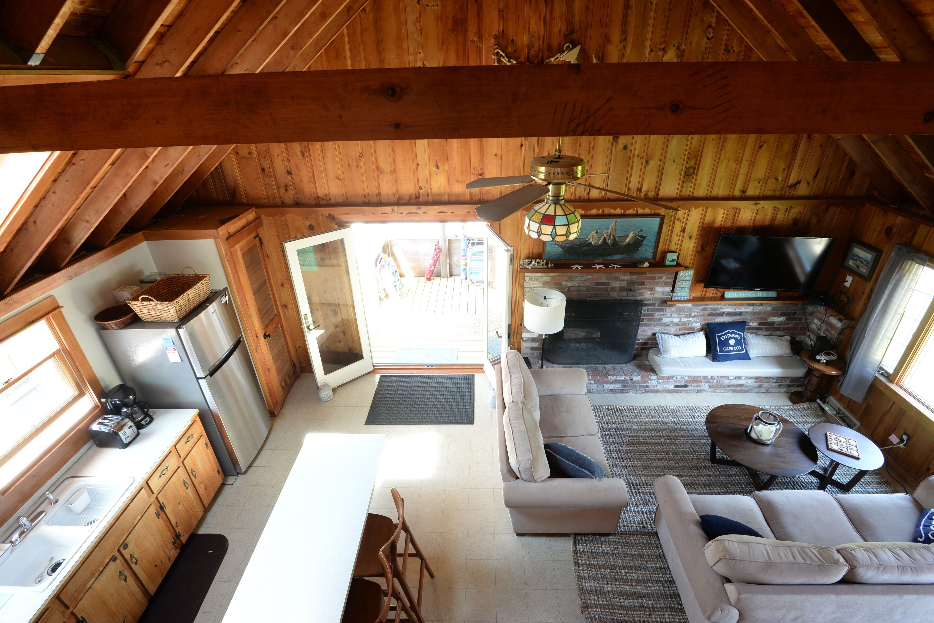 Een knus interieur met een houten plafond, een open haard, een bank en een televisie.