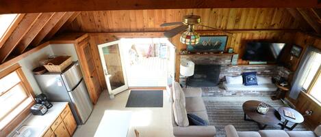 Een knus interieur met een houten plafond, een open haard, een bank en een televisie.